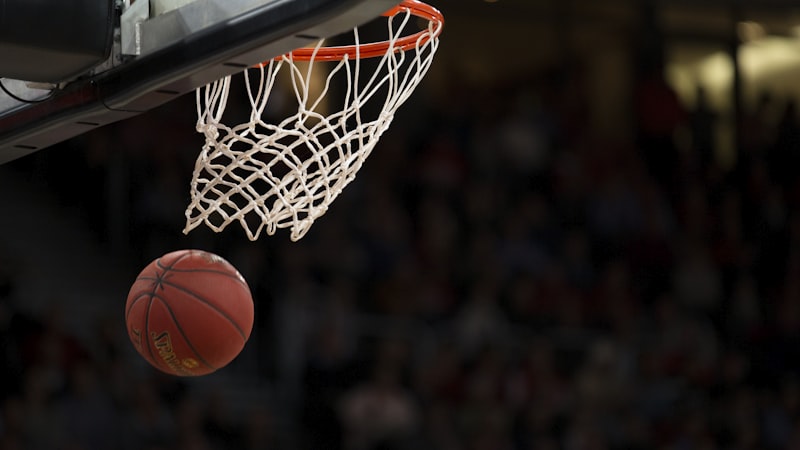 NBA球员在比赛中高高跃起扣篮的精彩瞬间，背景是清晰的篮筐